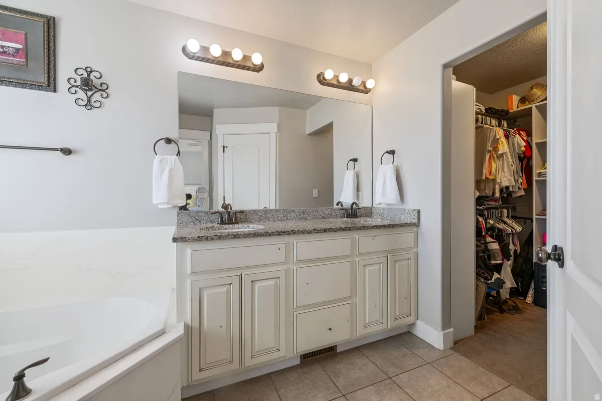 Spacious bathroom featuring a double vanity with granite countertop, dual sinks, and under-cabinet storage