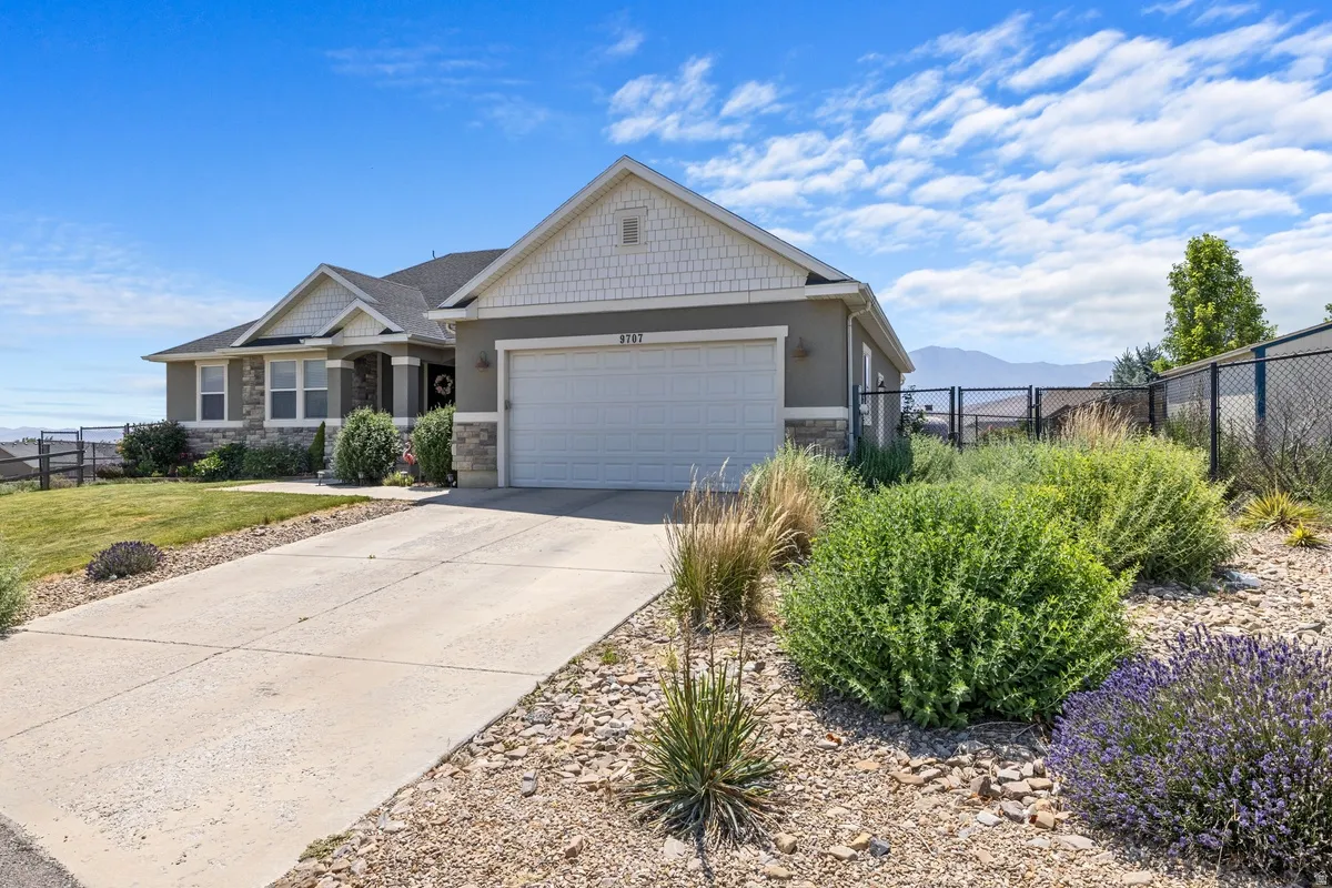 Ranch-style residence featuring a prominent two-car garage, stone and siding exterior accents, and a concrete driveway