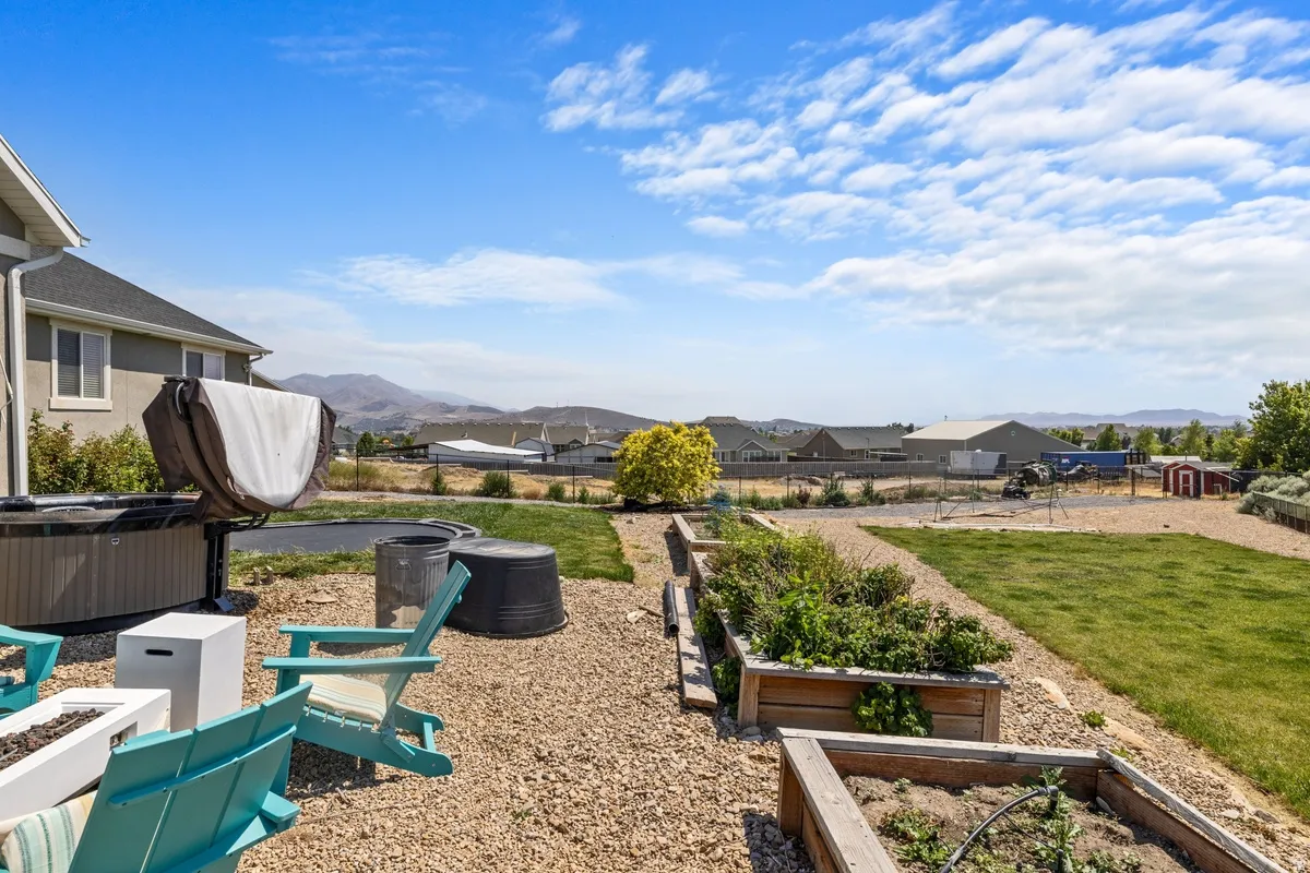 Expansive outdoor space featuring gravel ground cover, a manicured lawn area, and multiple raised garden beds