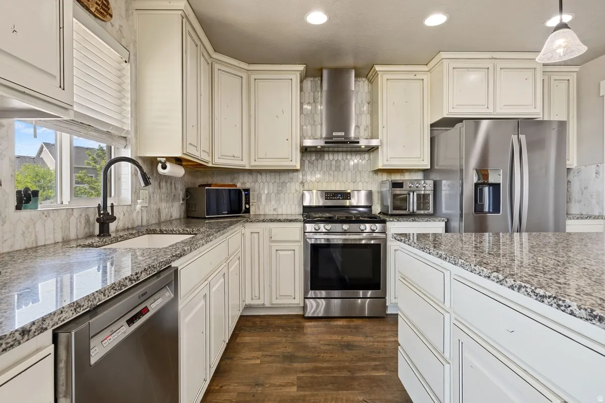 Kitchen featuring white cabinetry, granite countertops, wood-finish flooring, stainless steel appliances, and a tiled backsplash