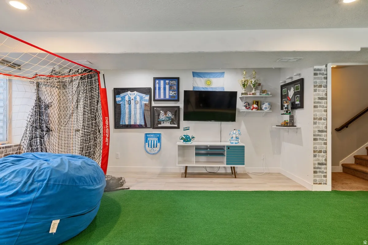 Recreational space featuring green turf flooring and wood-finish flooring
