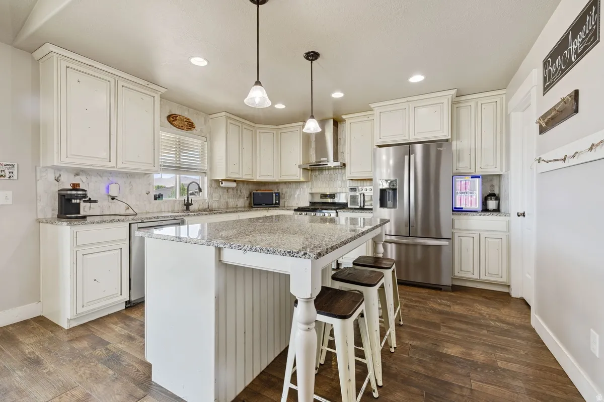 White cabinetry kitchen featuring a center island, stainless steel appliances, wood-finish flooring, and recessed lighting