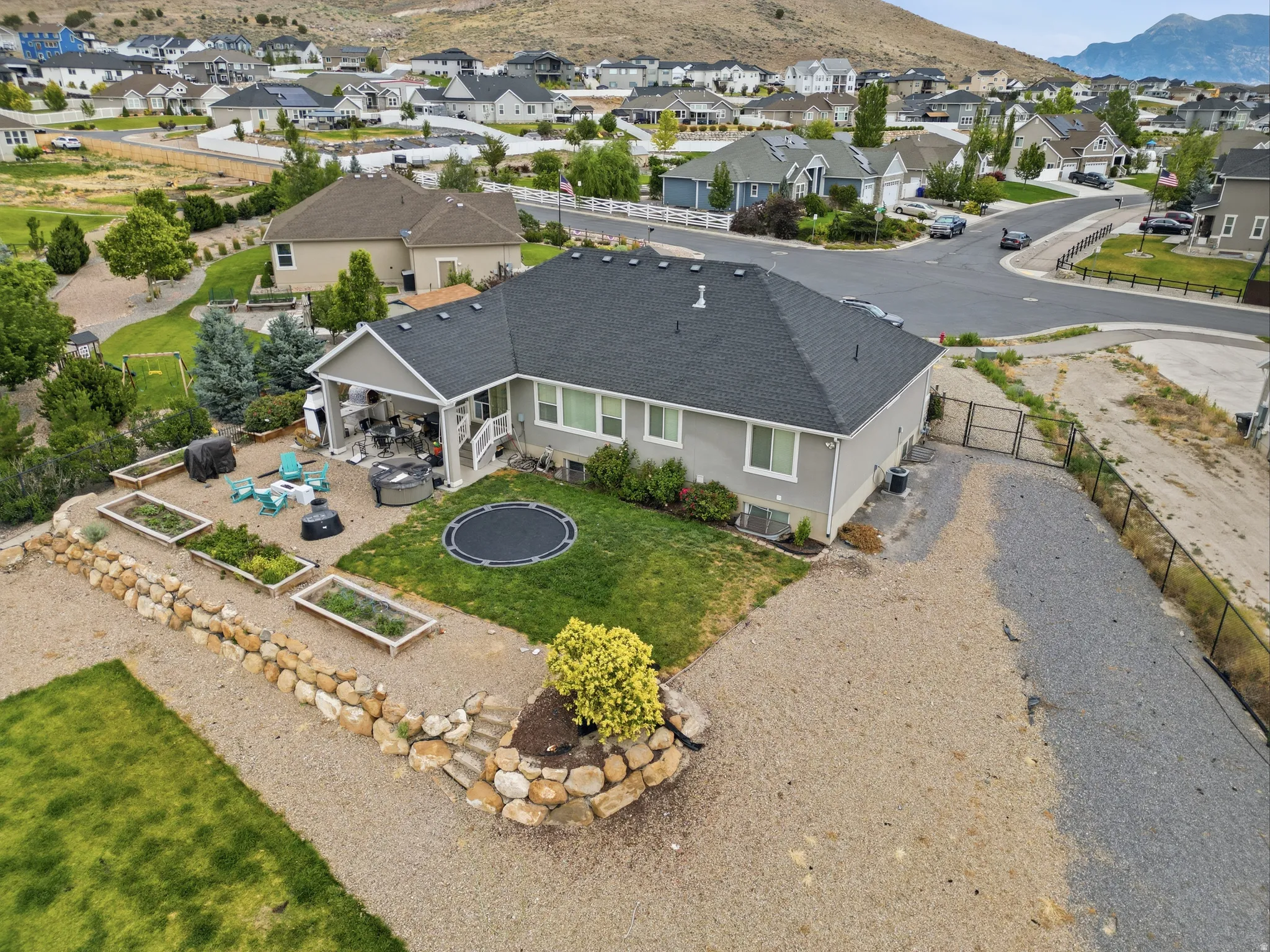 Rear exterior featuring a covered patio, a manicured lawn, and raised garden beds