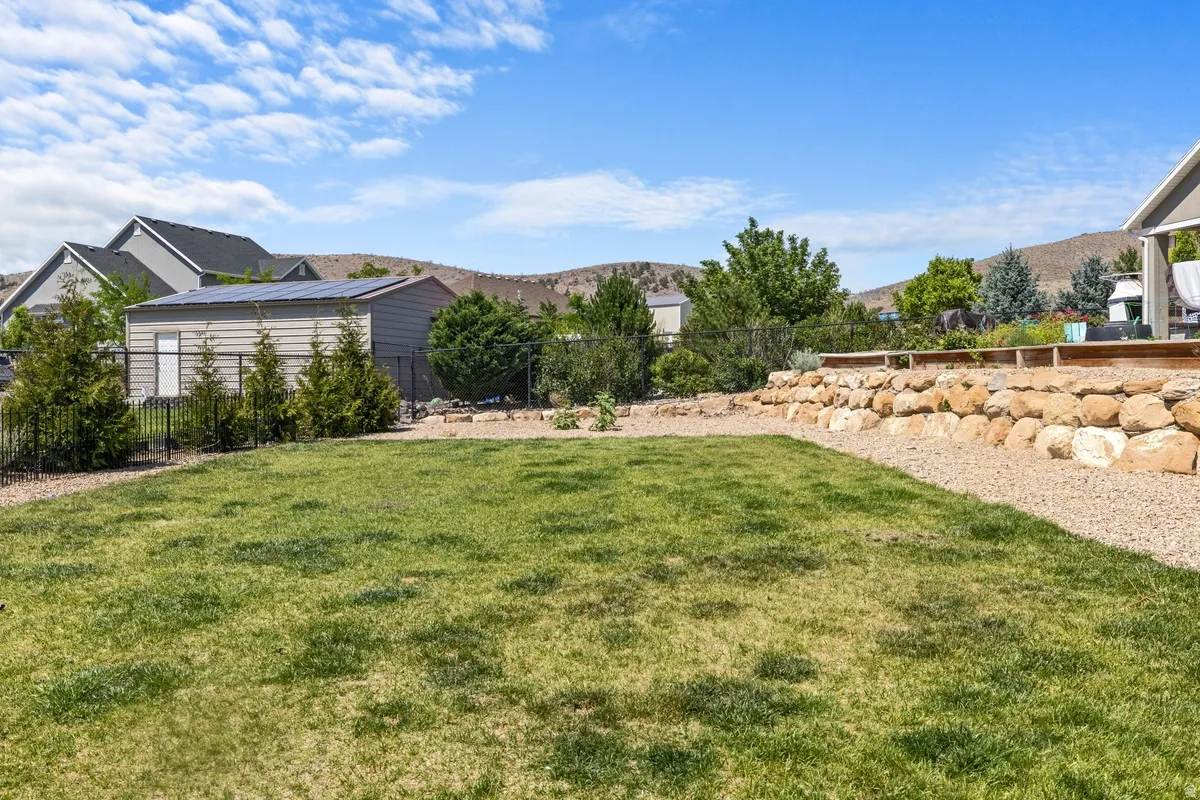 Expansive backyard featuring a lush lawn, gravel hardscaping, and a stone retaining wall