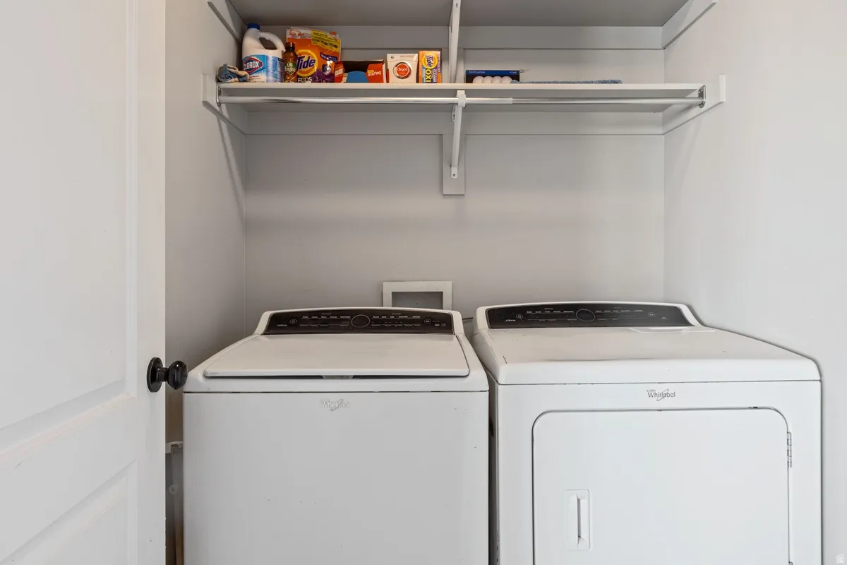 Dedicated laundry area featuring a white washer and dryer set, overhead shelving, and a hanging rod