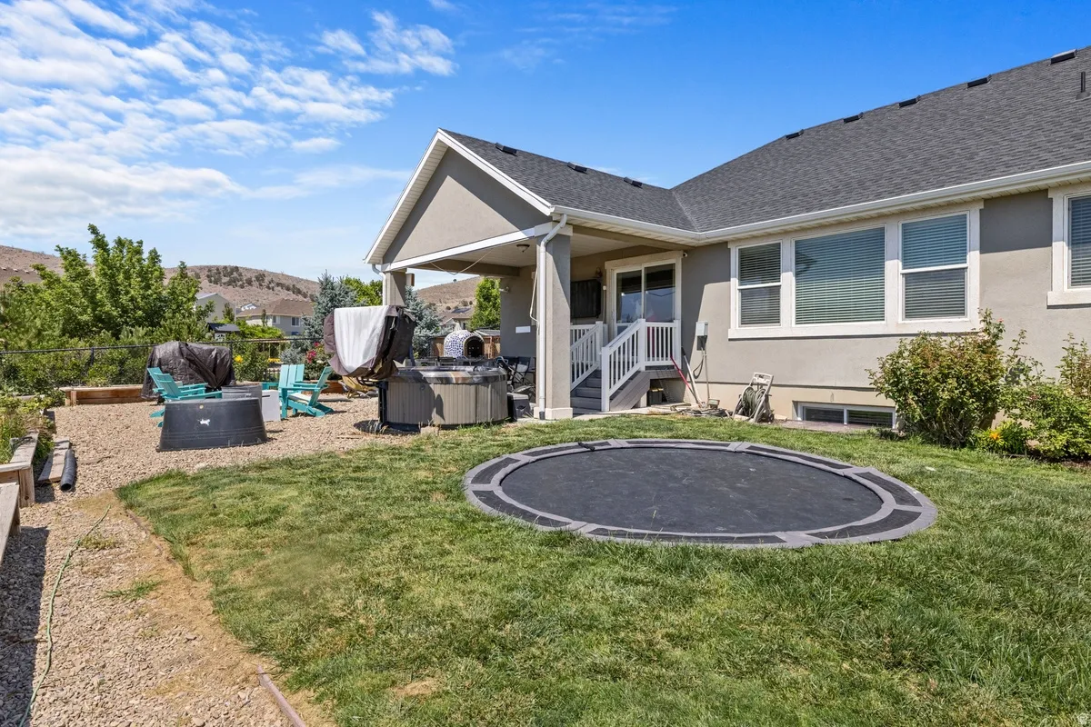 Expansive backyard featuring a covered patio, built-in ground trampoline, and a gravel entertainment area