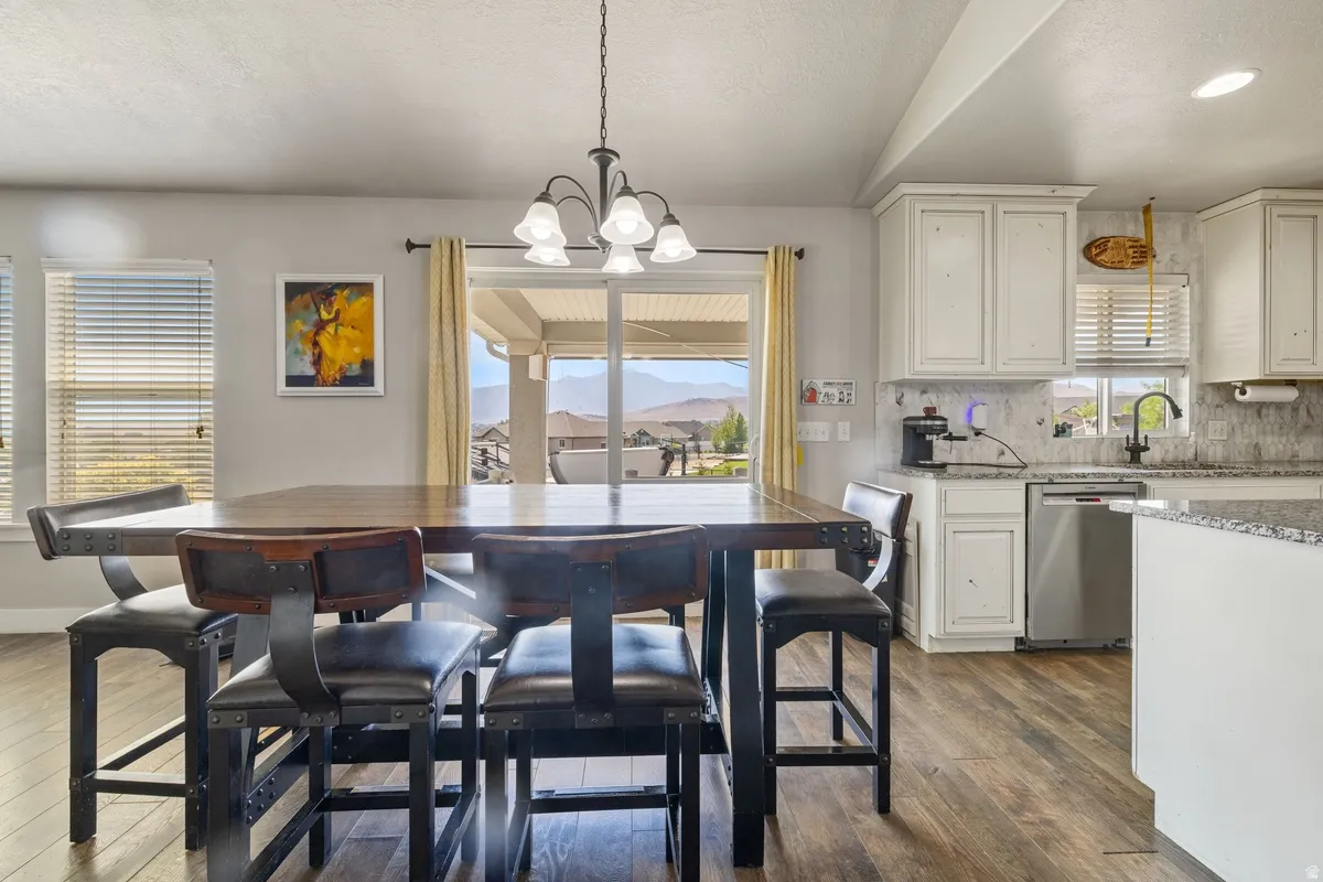 Open concept living area featuring wood-finish flooring, white cabinetry, a sliding glass door, and a kitchen island with a granite-style countertop