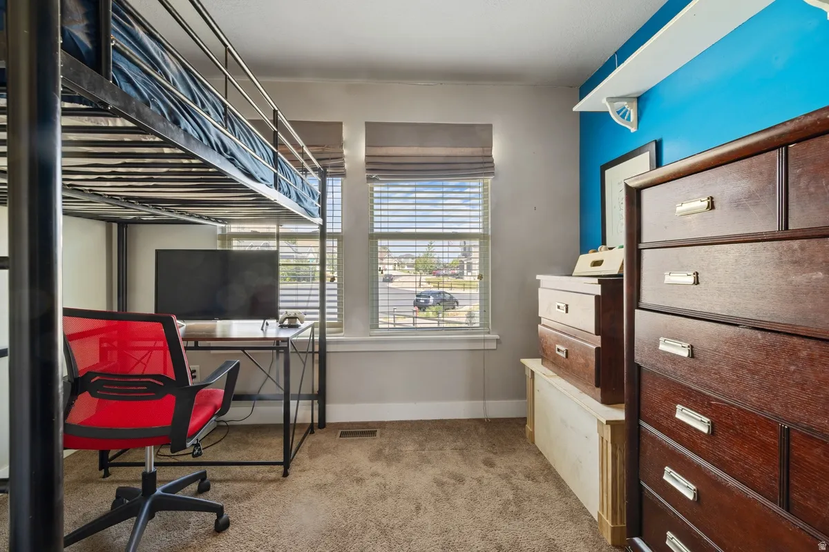 Carpeted room with double windows featuring blinds, a built-in wall shelf, and a painted accent wall