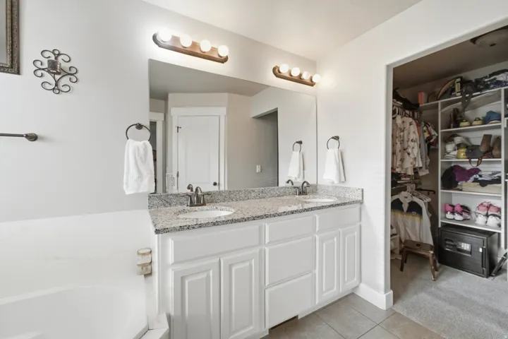 Dual vanity with granite-style countertop, undermount sinks, and white shaker-style cabinetry