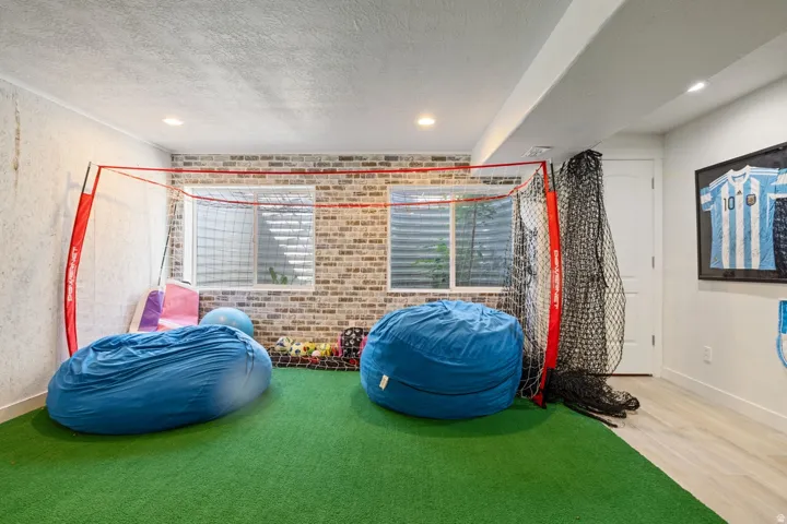 Recreational room featuring artificial turf flooring and a brick-pattern accent wall