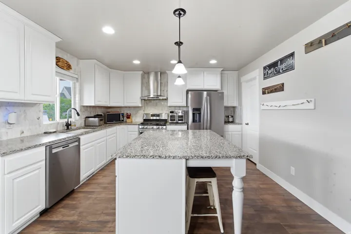 Kitchen featuring white cabinetry, wood-finish flooring, recessed lighting, and a center island with a speckled countertop