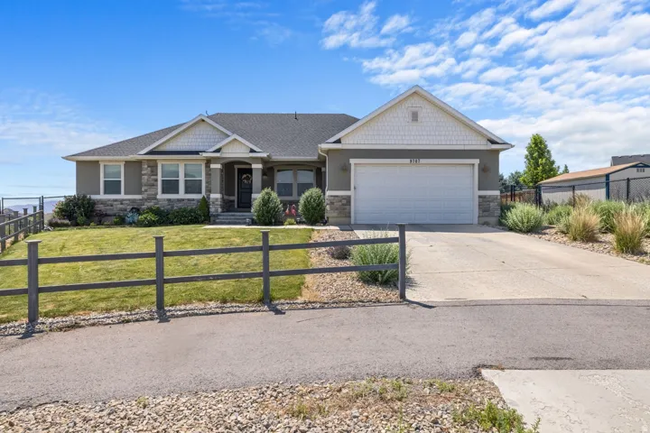 Ranch-style residence featuring a split-rail fence, attached two-car garage, and a concrete driveway