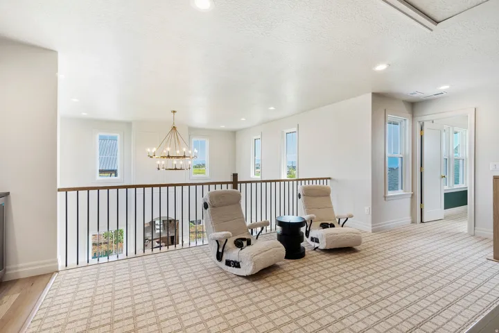 Open loft area featuring patterned carpet and a dark wood-finish railing with black iron balusters