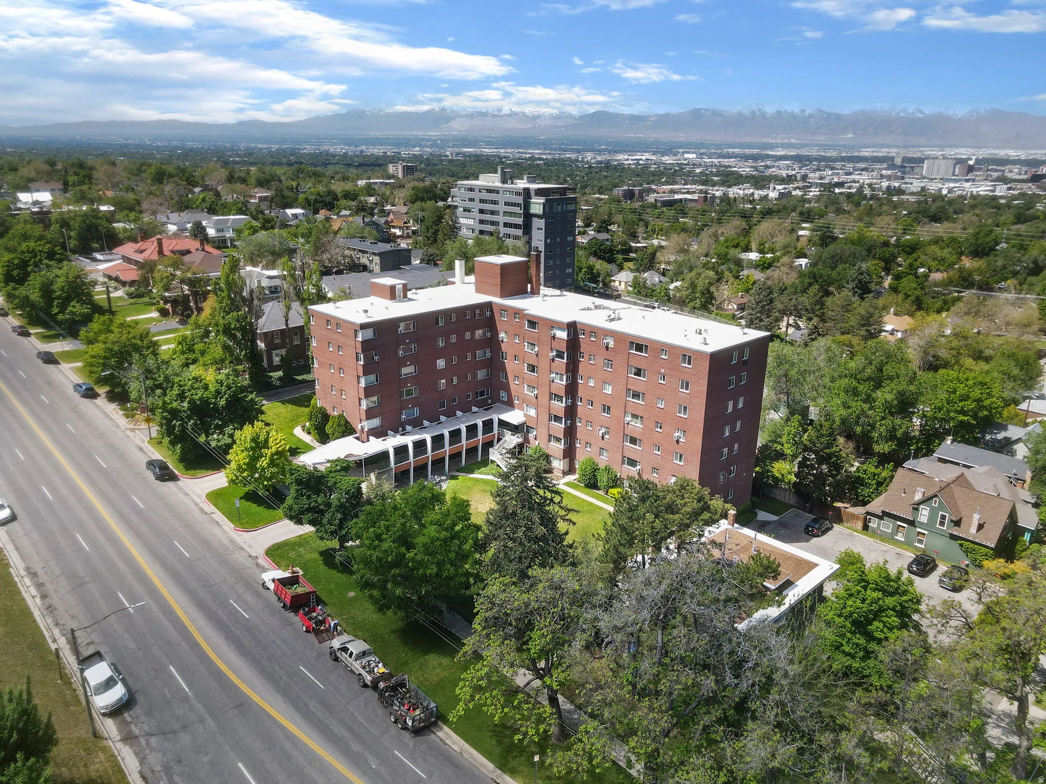 Red brick multi-story building featuring multiple windows, a flat roof, and a distinct lower-level portico with columns