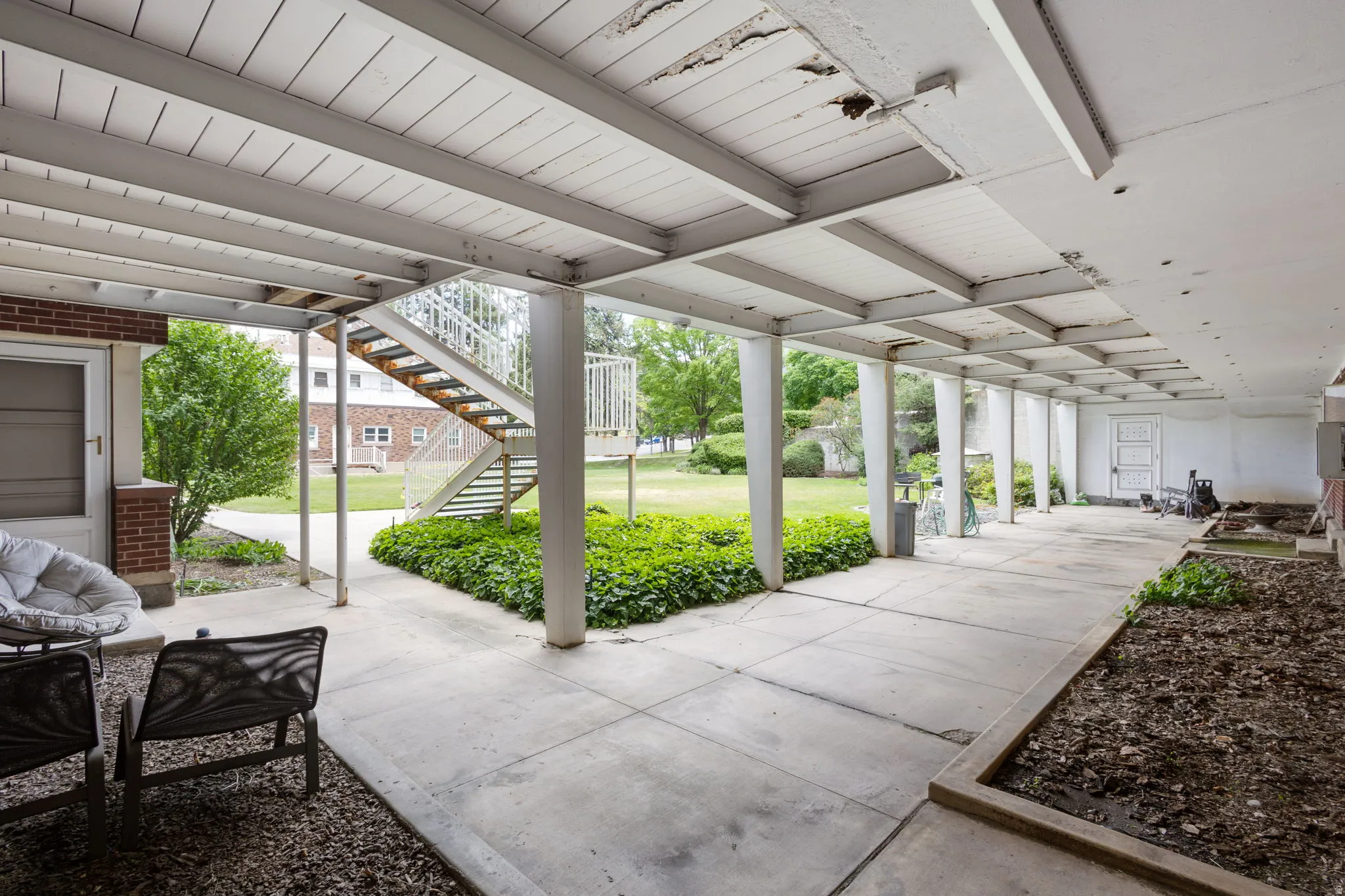 Covered concrete walkway with brick accent walls and an exposed metal staircase