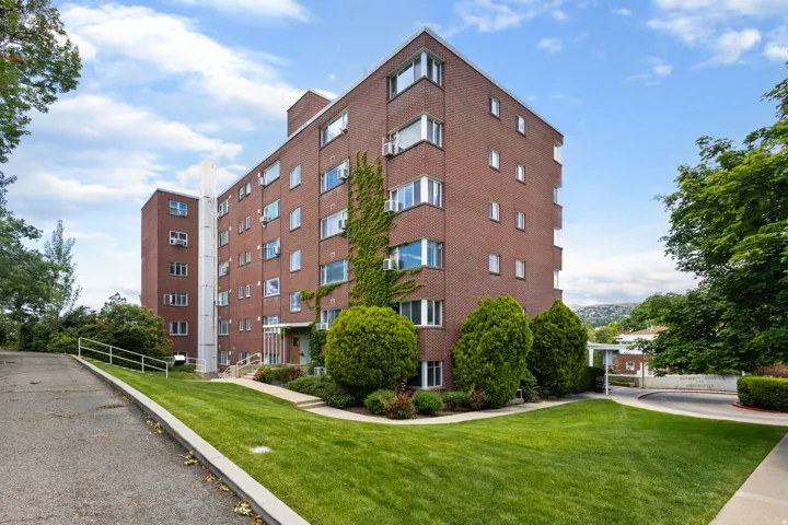 Brick facade building featuring multiple large windows, mature climbing ivy, and a well-maintained lawn