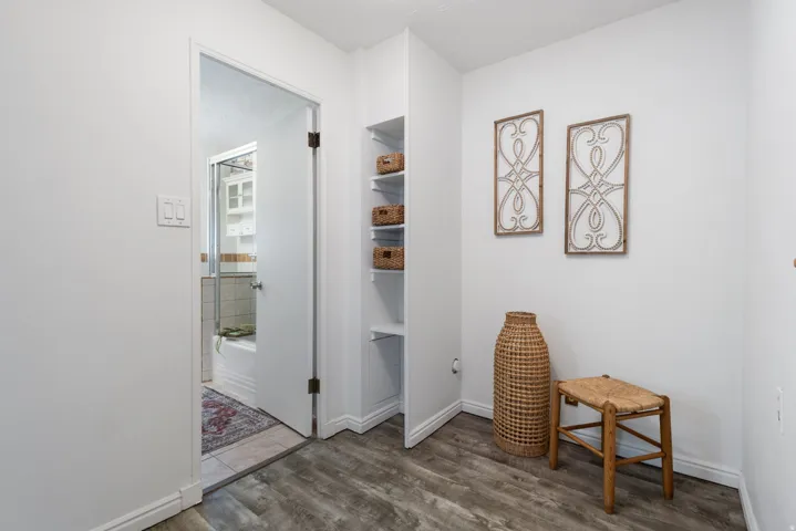Hallway featuring wood-finish flooring and integrated shelving