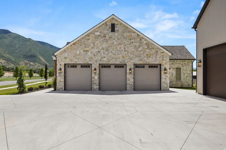 Stone facade garage with three carriage-style doors and exterior sconce lighting