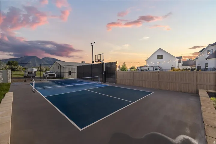 Dedicated sports court featuring a pickleball net and basketball hoop