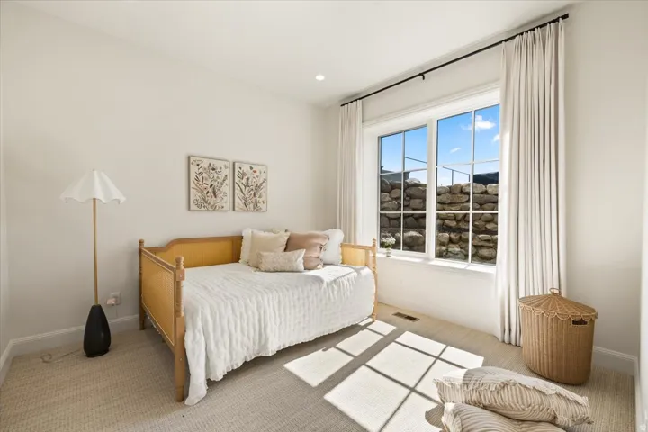 Bright room featuring a large window with white trim, recessed lighting, and light-toned carpet flooring