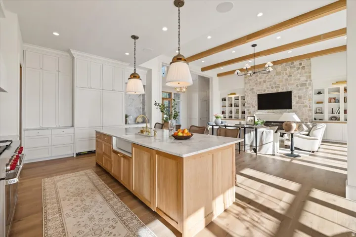 Gourmet kitchen island with a light wood base and stone countertop, featuring an integrated sink and pendant lighting