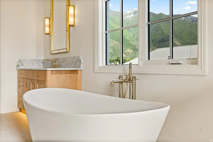 Freestanding soaking tub with a floor-mounted gold-toned tub filler