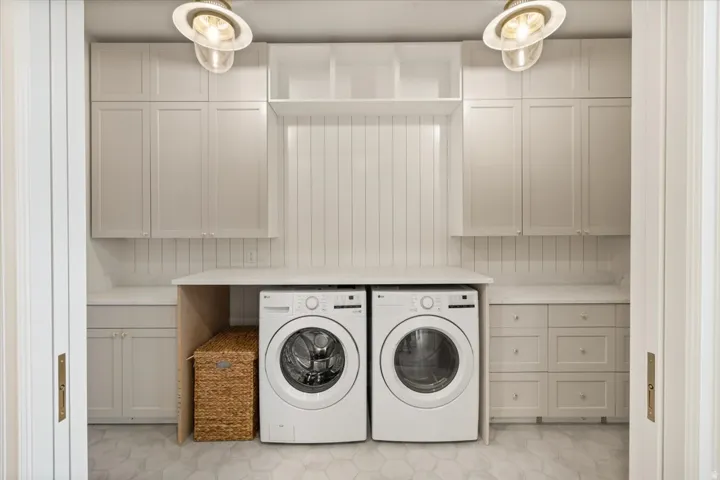 Laundry area featuring hexagonal floor tile, beadboard wall paneling, extensive cabinetry, and a countertop work surface