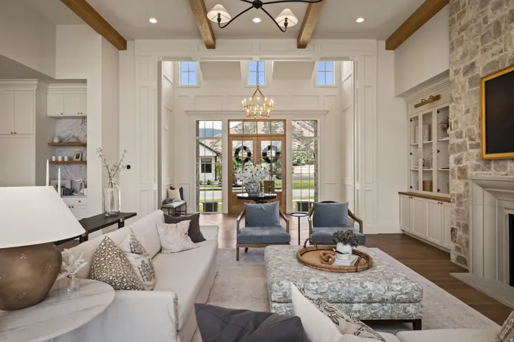 Spacious living area featuring exposed wood beams, a stone-clad fireplace, and hardwood flooring
