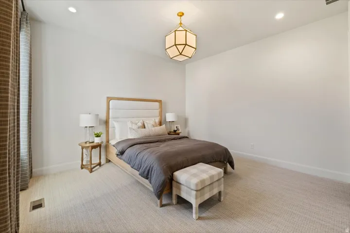 Spacious room featuring light-colored carpeting, recessed lighting, and a prominent geometric brass chandelier