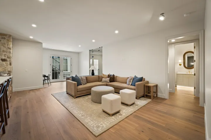 Spacious living area featuring light wood-finish flooring, recessed lighting, and a stone accent wall