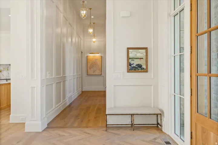 Herringbone wood-finish flooring extending into a hallway with recessed panel wainscoting