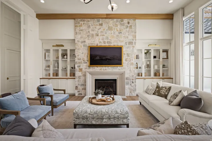 Stone-clad fireplace with a classic mantelpiece, flanked by built-in cabinetry with glass-front uppers and recessed lighting