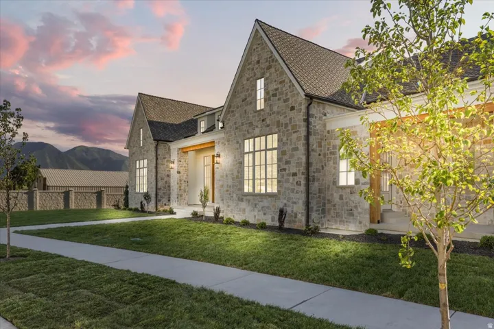 Stone facade residence featuring a prominent gabled roofline, multiple large windows with grid patterns, and a covered entryway with wood-toned accents
