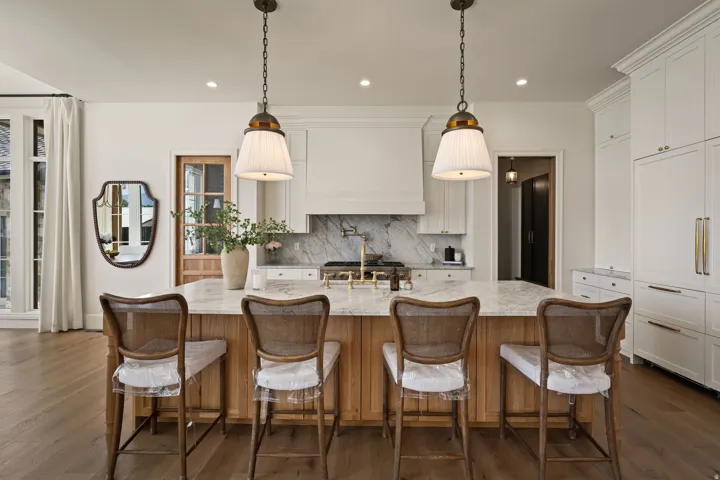Central kitchen island with a natural wood-finish base, light-toned countertop, and dual pendant lighting