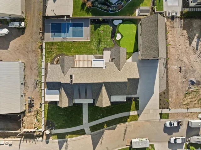 Expansive property featuring a paved driveway, a multi-sport court with basketball hoops, a putting green, and a generously sized residence