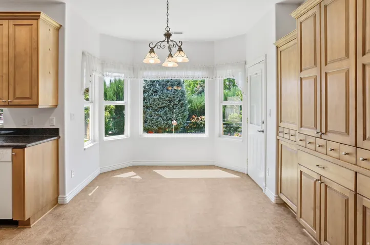 Bay window dining area with a multi-light chandelier and carpet flooring