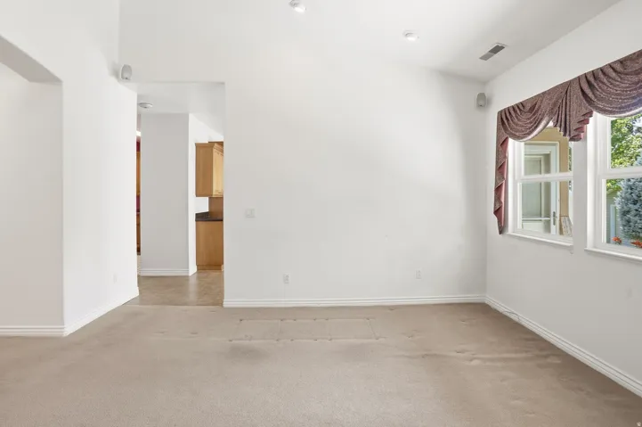 Bright interior space featuring recessed lighting, a window with exterior views, and a doorway opening to an additional room with wood-finish cabinetry