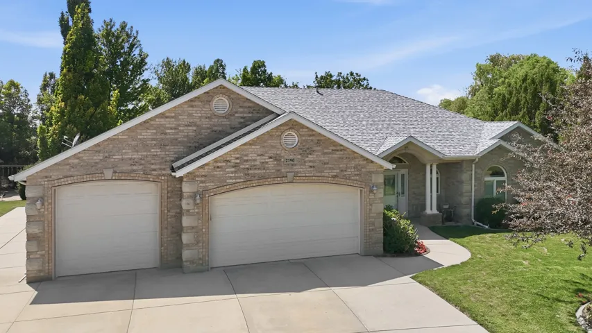 Brick exterior featuring a two-car garage with arched entrances, a concrete driveway, and a curved sidewalk leading to the main entrance