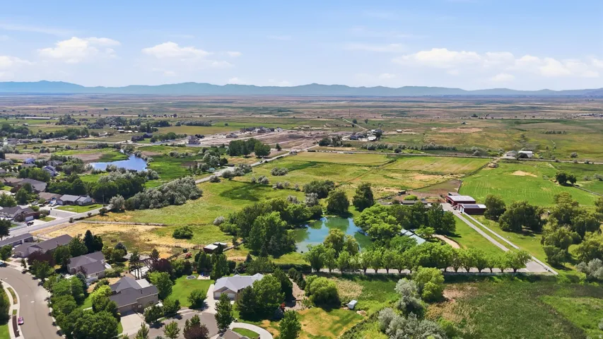 Expansive rural landscape featuring a private pond, mature trees, and agricultural fields
