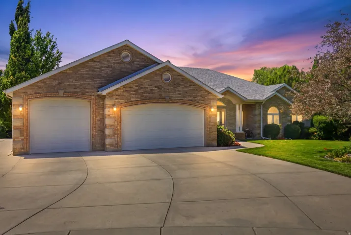 Brick veneer facade with arched garage doors, a two-car garage, and a concrete driveway