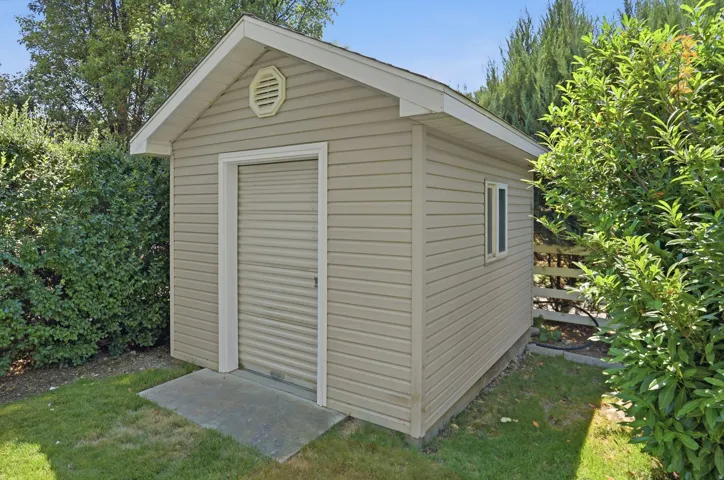 Detached storage shed featuring horizontal siding, a roll-up door, a single window, and a concrete pad