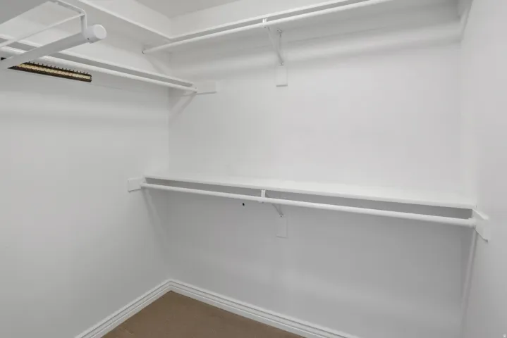 Walk-in closet with white shelving and hanging rods