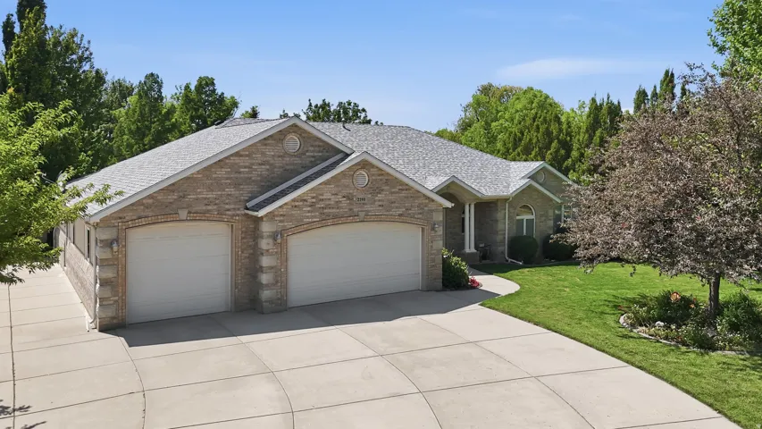 Spacious brick exterior home featuring a two-car garage, concrete driveway, and a manicured lawn