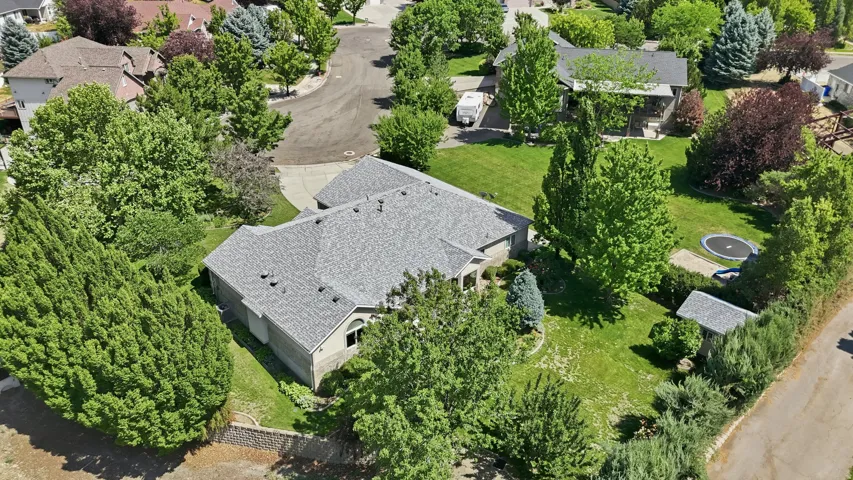 Residential property on a corner lot featuring a gray shingle roof and a paved driveway