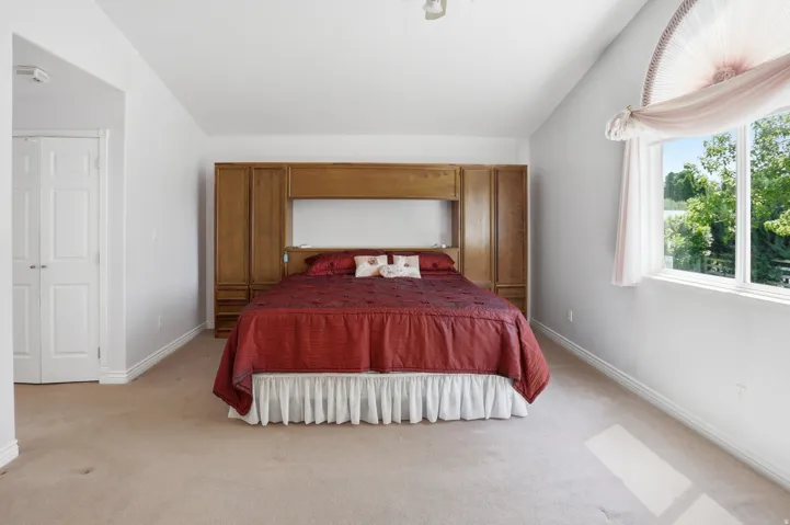 Spacious room with built-in wood cabinetry, light beige carpeting, and a large window