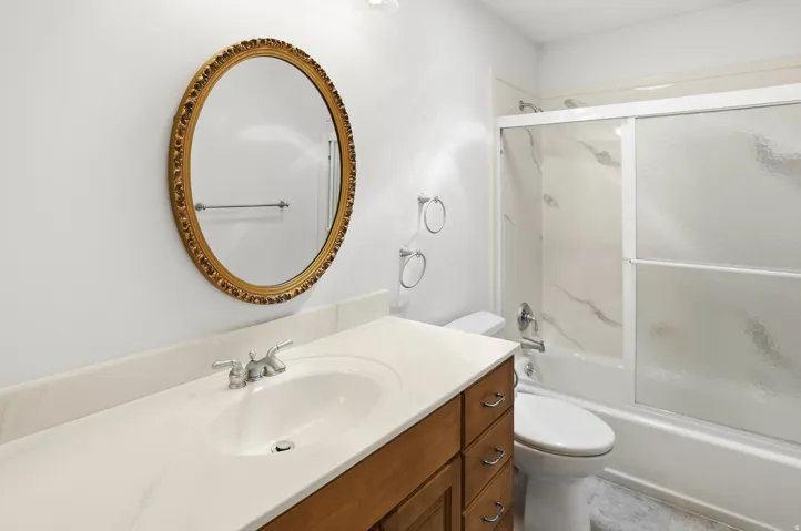 Bathroom featuring a single vanity with wood-finish cabinetry, a light-toned countertop, and a built-in sink
