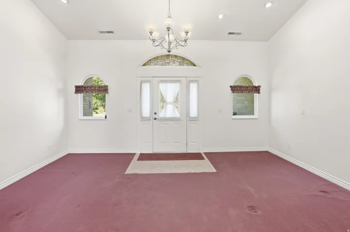 Entryway featuring a double door with glass inserts, an arched transom window with stone detailing, and two arched windows