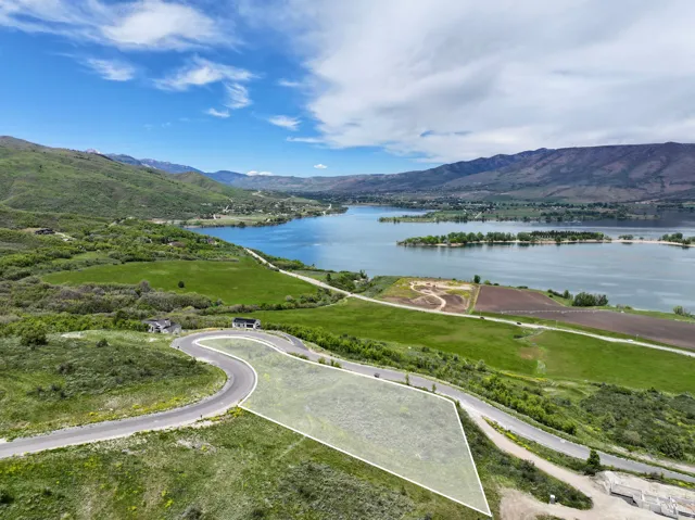 Expansive lot with a marked boundary, featuring a curved paved road and lush green surroundings