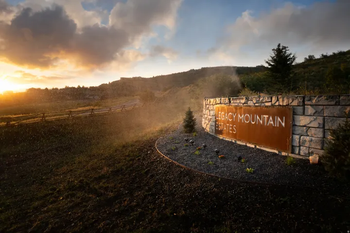 Stone entry monument featuring a large metal sign with "Legacy Mountain Estates" typography