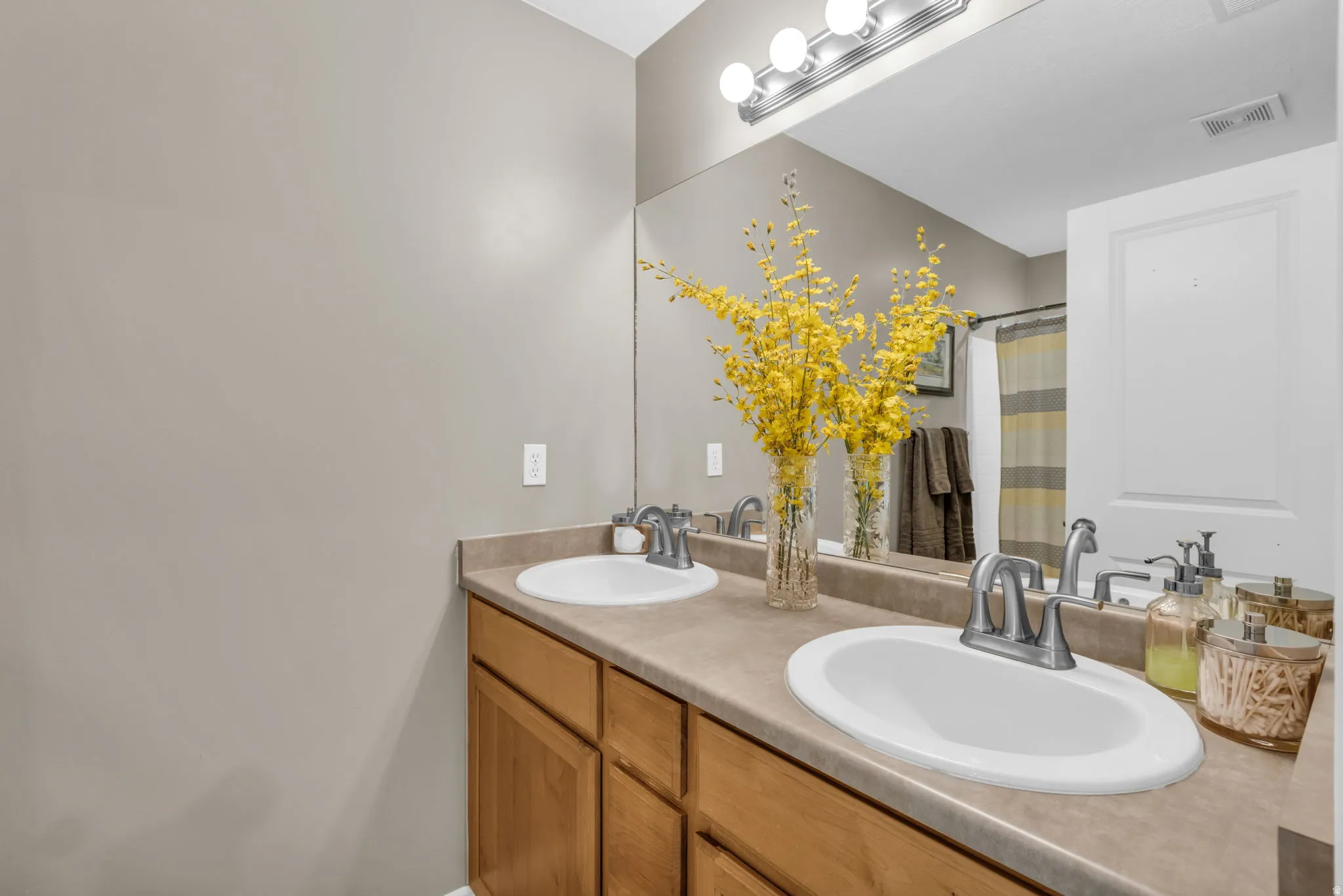 Dual vanity featuring light wood-finish cabinetry and a neutral countertop